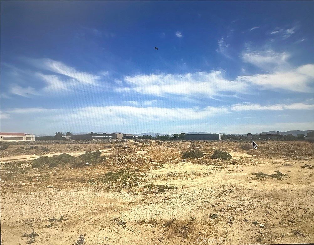 Seven acres of flat commercial land in Lancaster, California, with the Antelope Valley horizon and distant San Gabriel mountains
